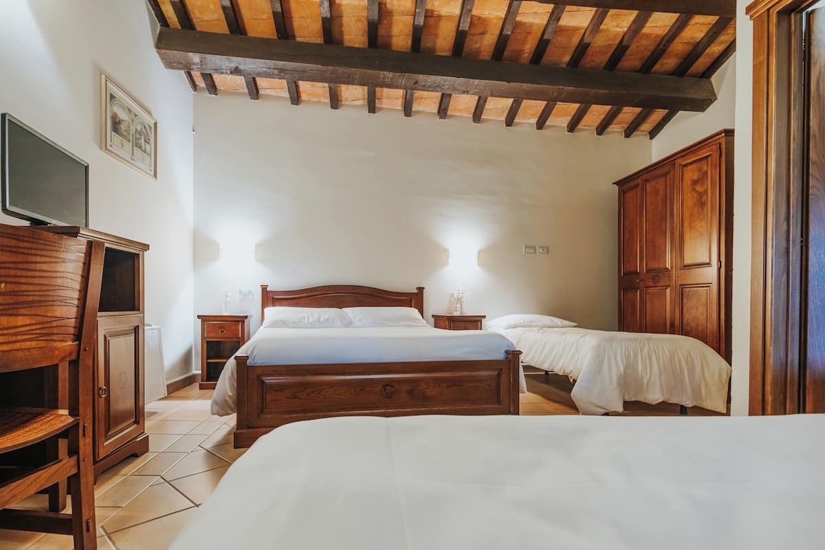 Ein Schlafzimmer mit zwei Holzbetten, einem Holzschrank, einem Fernseher und einem Fliesenboden.