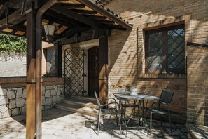 A patio with a table and chairs, a wooden pergola, and a stone wall. - Villaggio Rurale Le Sette Querce (Sesto Campano)