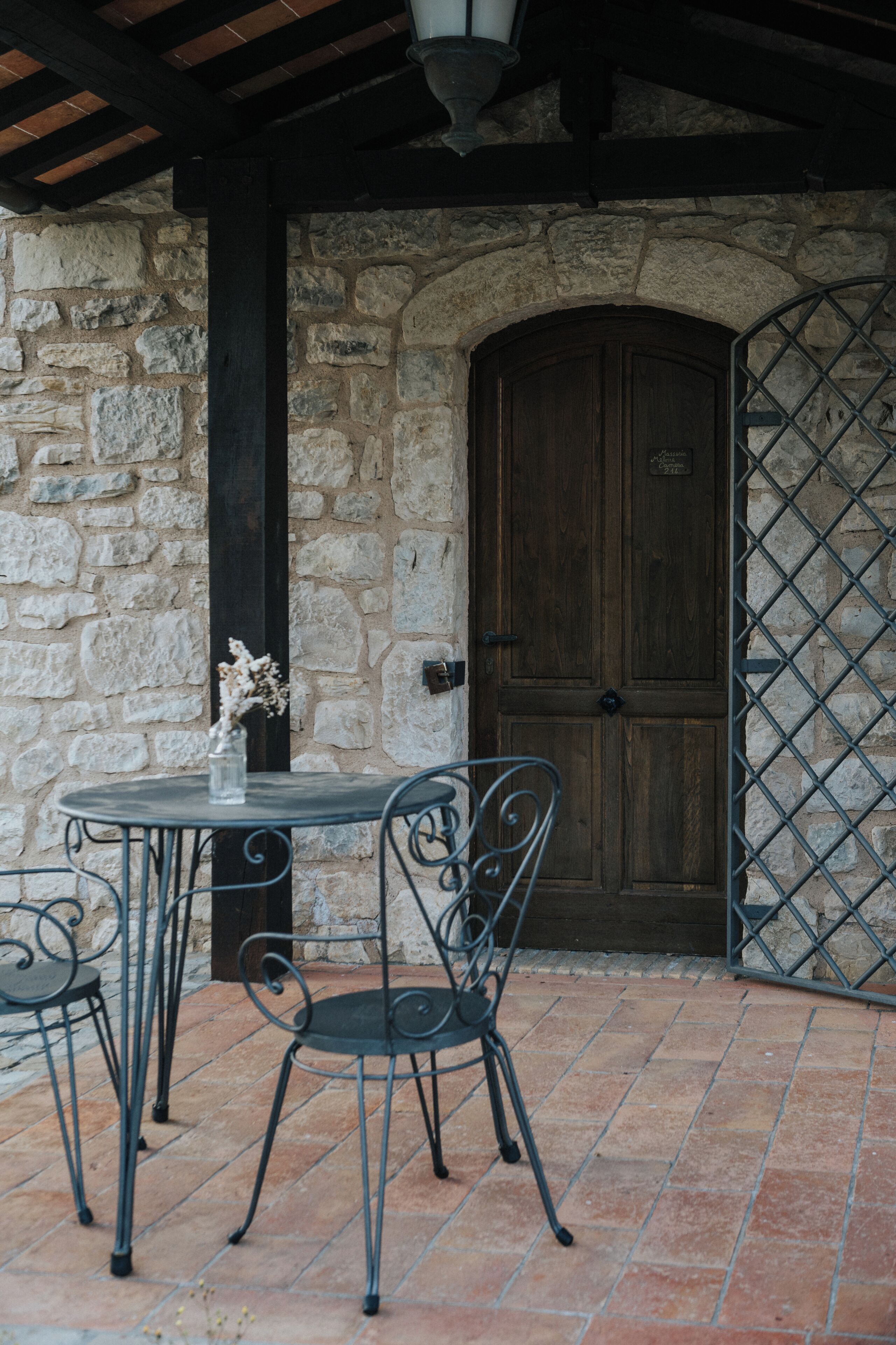 A stone wall with a wooden door, a metal gate, and a table with chairs.