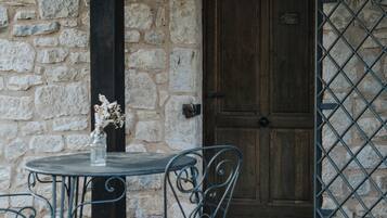 A stone wall with a wooden door, a metal gate, and a table with chairs.