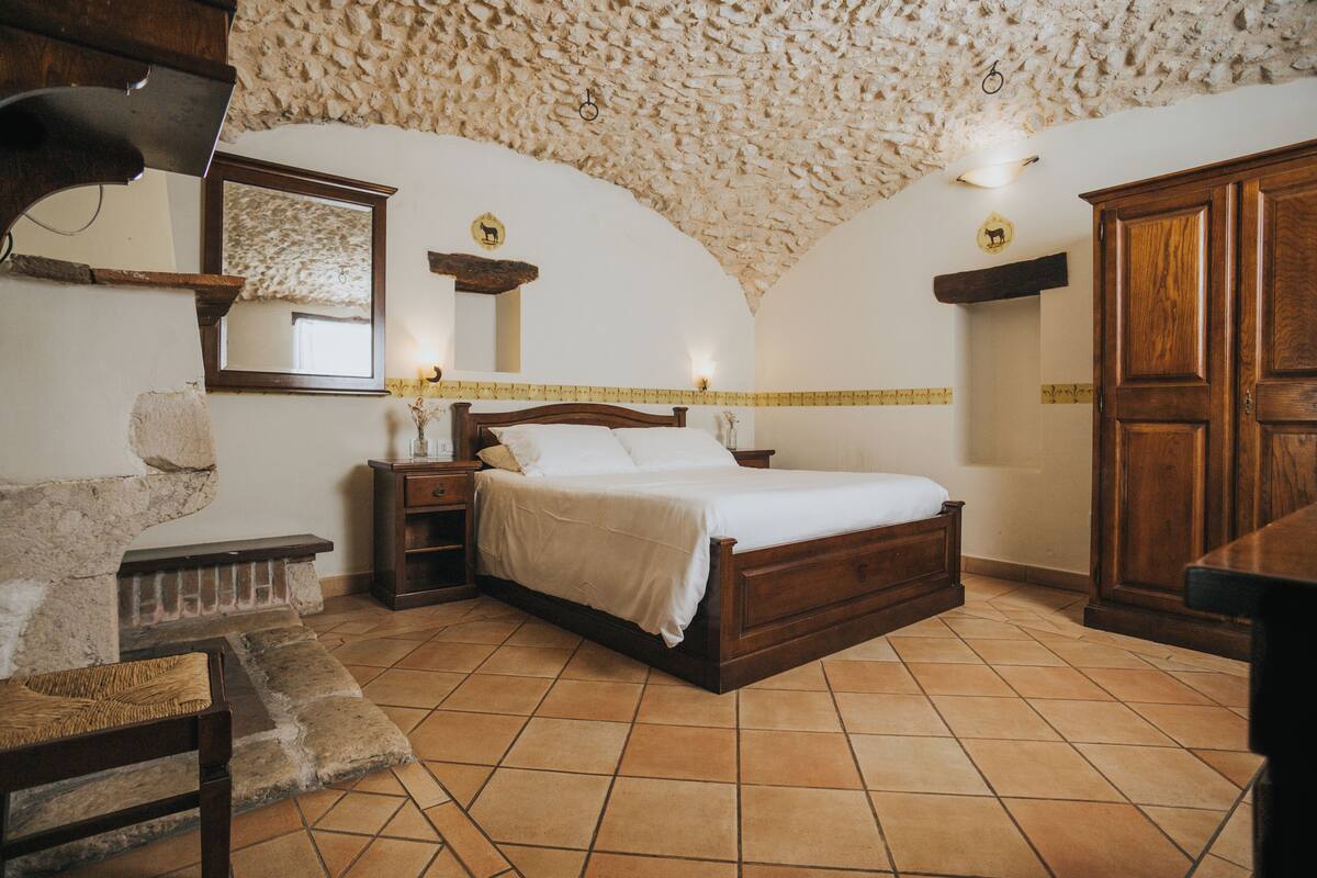 Ein Schlafzimmer mit einem Holzbett, Steinwänden und einem gefliesten Boden.