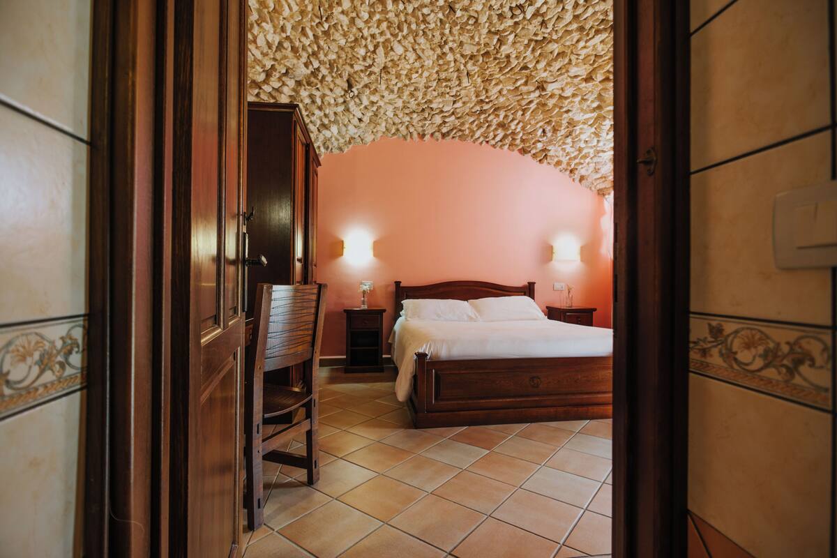 Ein Schlafzimmer mit einem Bett, Nachttischen und einem Holzsessel.
