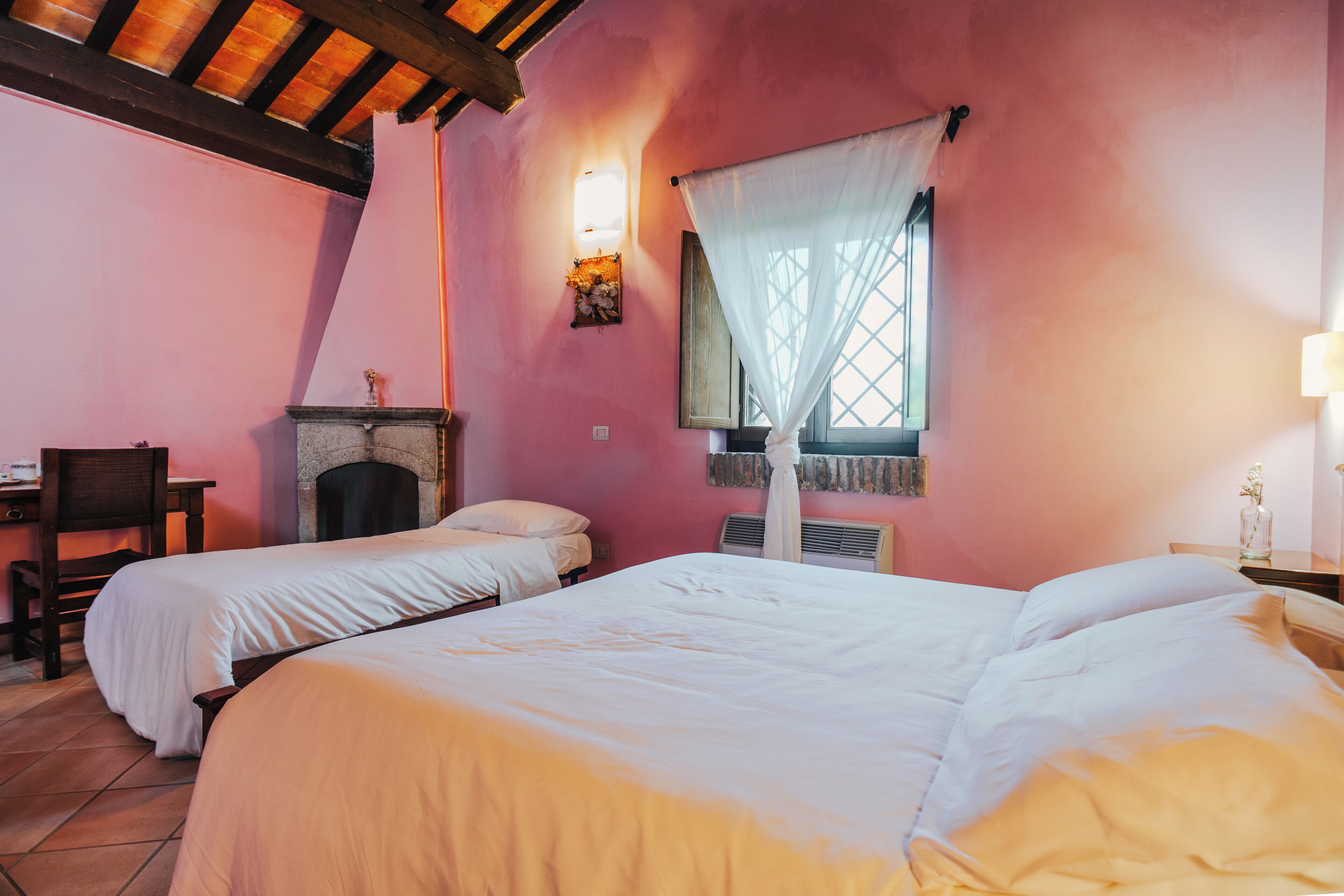 Una habitación con dos camas, un escritorio y una chimenea.