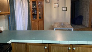 A kitchen with wooden cabinets, a countertop, a stove, a cabinet with glass doors, and a chandelier.