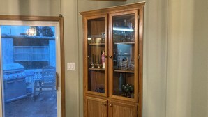 A wooden cabinet with glass doors containing various items.