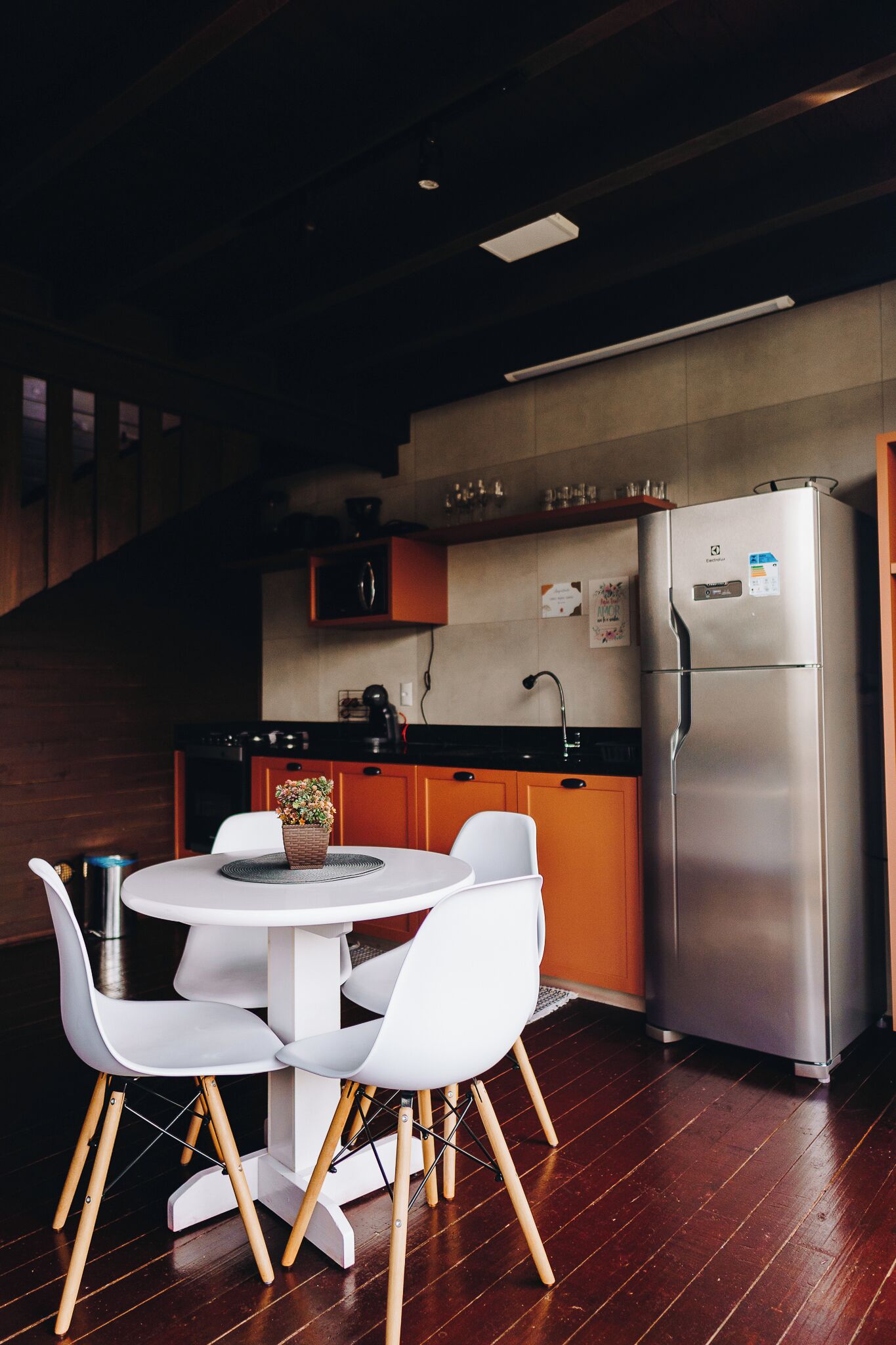 A modern kitchen with wooden cabinets, a stainless steel refrigerator, and a round dining table with white chairs.
