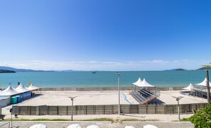 A beachside view with a sandy area, tents, and umbrellas. - Great Beachfront Apartment Lbm306 (Florianópolis)