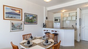 A dining area with a round table, chairs, and a kitchen in the background. - Great Beachfront Apartment Lbm306 (Florianópolis)