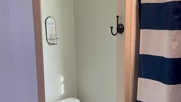 Een badkamer met een wit toilet, een handdoekhouder en een gestreepte douchegordijn.