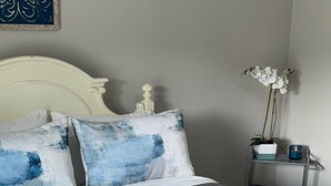 A neatly made bed with a grey quilt, a white headboard, and two pillows with blue and white patterns. - The Porter Blue (Augusta)