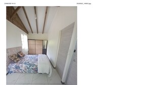 A bedroom with a bed, a wardrobe, and a door. - Country bungalow (Le Moule)