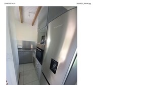 A modern kitchen with a stainless steel refrigerator, a built-in oven, and a microwave. - Country bungalow (Le Moule)