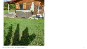A wooden cabin with a red roof, a hot tub, and an air conditioning unit. - Country bungalow (Le Moule)