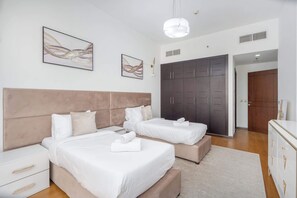 A modern bedroom with two beds, a wardrobe, and artwork on the walls. - Spacious 2 Bed in Al Barsha Sleeps 4 With Balcony (Dubai)