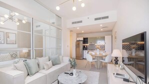A modern living room with a sofa, coffee table, and dining area. - Dubai Hills for 4 People in a Great Location (Dubai)