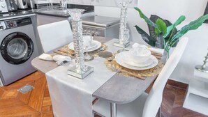 A dining area with a table set for four, including crystal glassware and white plates. - Production City Sleeps 4 With Water Views (Dubai)