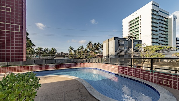 Una piscina con bordes de azulejos, rodeada por un deck con baldosas rojas y azules.