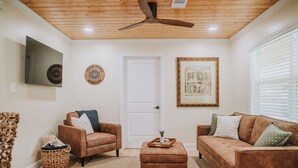 A living room with two brown sofas, a wooden ceiling fan, a white door, and a framed picture on the wall. - 2BR/1BA in Golf Cart District near Beaches and Downtown! The Beachcomber A (Ocean Springs)