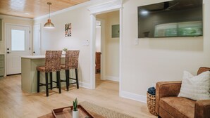 A modern living room with a brown sofa, two patterned chairs, a coffee table, and a TV mounted on the wall. - 2BR/1BA in Golf Cart District near Beaches and Downtown! The Beachcomber A (Ocean Springs)