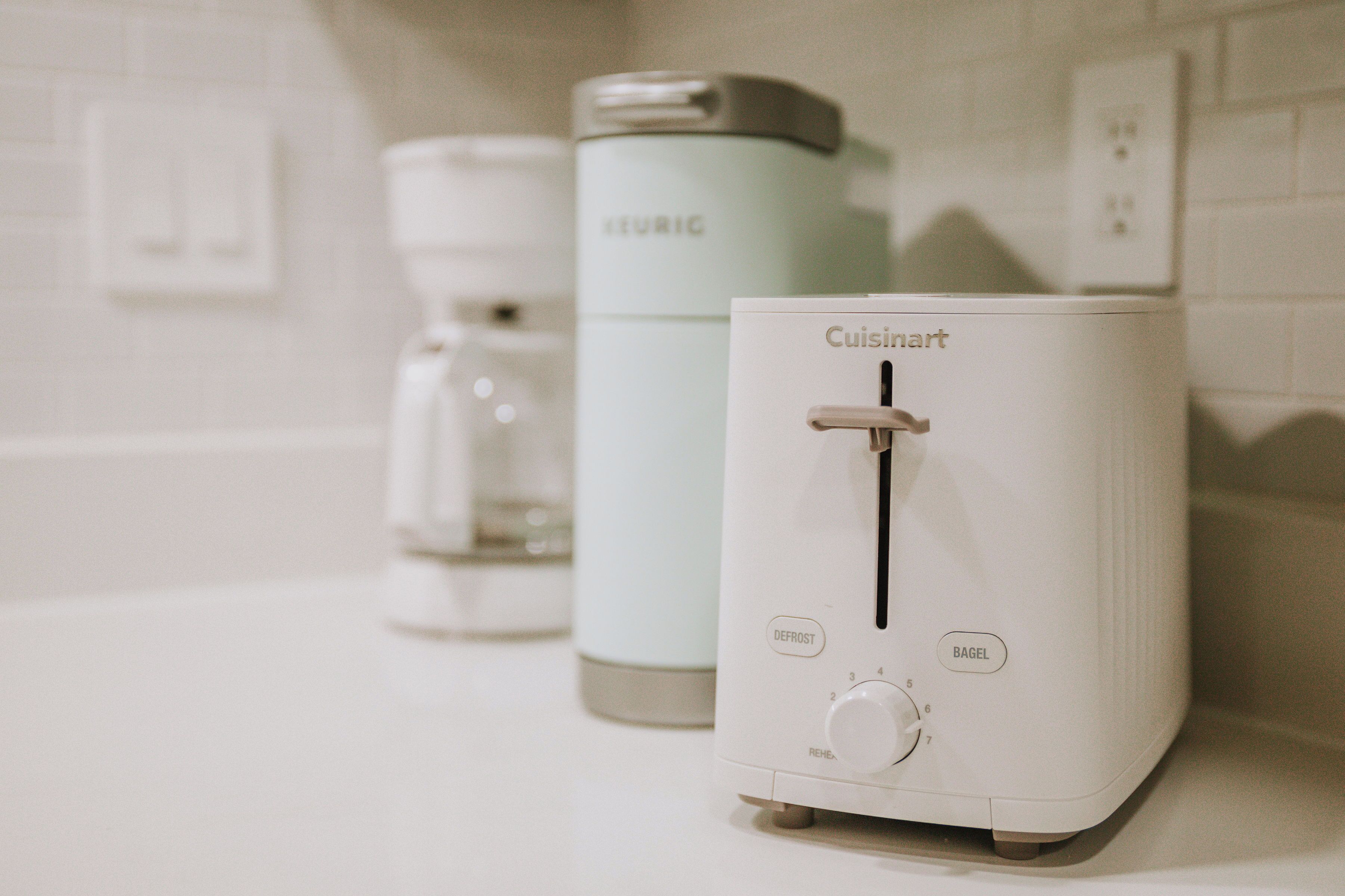 A kitchen with a Cuisinart toaster, a Keurig coffee maker, and a defrost setting on the toaster.