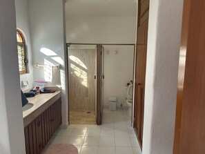A narrow hallway with a bathroom on the right, featuring a toilet and a sink.