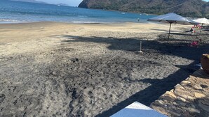 A beach with umbrellas and a mountain in the background. - Casa Lang 4 BR/Bath pool on flat calm beach steps to restaurants in secure area. (Manzanillo)