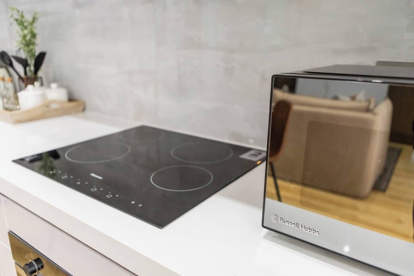 A modern kitchen with a built-in induction cooktop and a glass-enclosed oven.