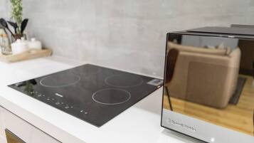 A modern kitchen with a built-in induction cooktop and a glass-enclosed oven.