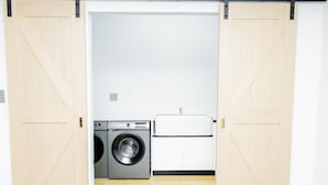 A laundry room with a washing machine, dryer, and a white cabinet.
