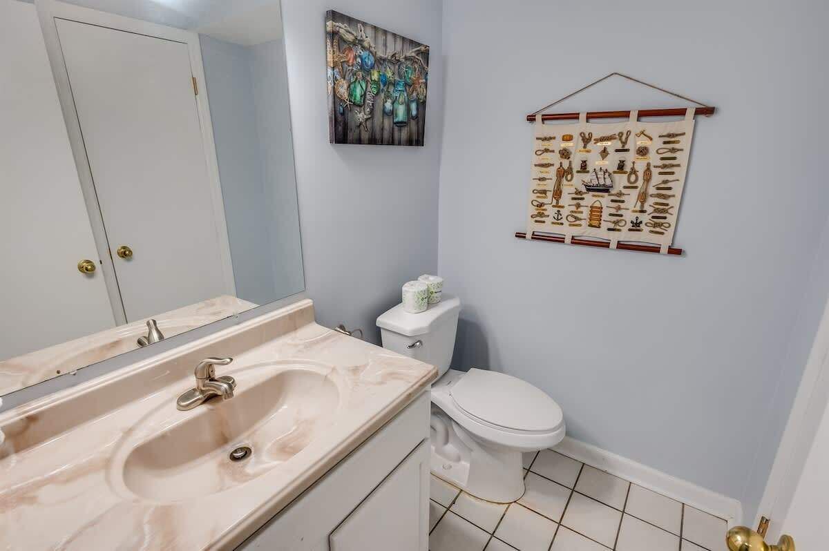 A bathroom with a marble sink, a toilet, and a wall-mounted art piece.