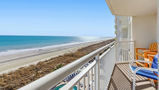 Ein Balkon mit Blick auf den Strand, einen Pool und Sitzgelegenheiten im Freien.