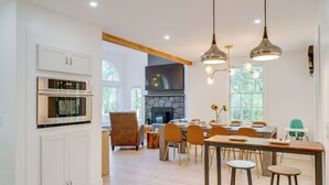 Een moderne keuken met inbouwapparatuur, een eethoek met houten meubels en een stenen openhaard.