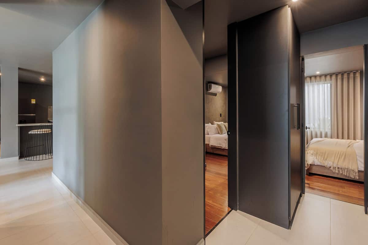 A modern hotel room with a large bed, a separate sitting area, and a kitchenette.