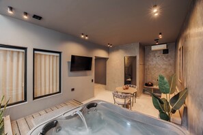 A modern bathroom with a hot tub, a flat-screen TV, and a small table with chairs. - 10th Street 3 Bedroom Jacuzzi & Billiard (Medellín)