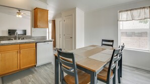 Una cocina moderna con armarios de madera, lavavajillas integrado y un comedor con mesa y sillas de madera.