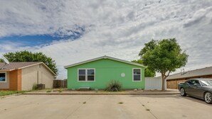 Una casa verde de un piso con un camino de entrada y un árbol en frente.