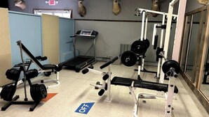 Ein Fitnessraum mit Trainingsgeräten, Laufband und Dekoration mit Hirschköpfen an der Wand.