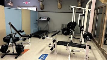 Une salle de sport équipée de matériel de musculation, de tapis de course et ornée de têtes de cerf au mur.