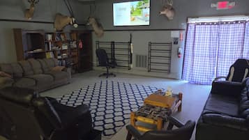 Un salon comprenant un canapé, des fauteuils, une table basse, une bibliothèque et des têtes d’animaux montées au mur.