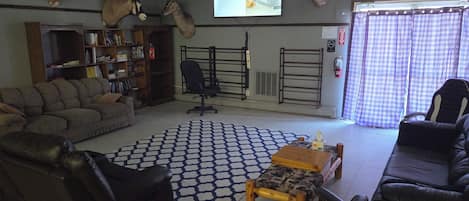 A living room with a sofa, chairs, a coffee table, a bookshelf, and mounted animal heads.