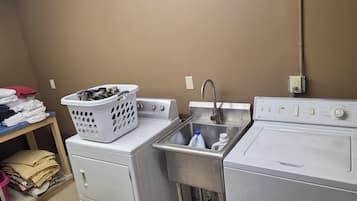 Un espace buanderie comprenant un lave-linge, un sèche-linge et un évier avec un robinet.