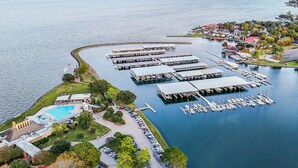 En vy från ovan över en småbåtshamn med flera bryggor, en swimmingpool och omgivande bostadsområden.