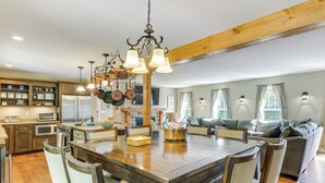 A spacious kitchen with a large wooden dining table, modern appliances, and a cozy living area with a sofa and windows. - Spacious home,ppong,darts,pick ball net, 6mi mt sn (Wilmington)