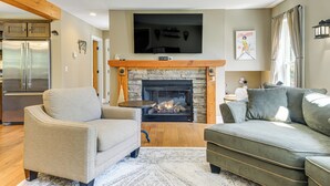 A living room with a stone fireplace, a flat-screen TV mounted above it, and a sofa. - Spacious home,ppong,darts,pick ball net, 6mi mt sn (Wilmington)