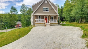 A two-story house with a red door, a porch, and a gravel driveway. - Spacious home,ppong,darts,pick ball net, 6mi mt sn (Wilmington)