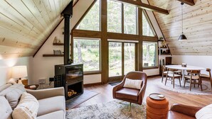 A cozy loft-style room with a fireplace, seating area, and large windows offering a view of the outdoors. - 1 Mi to Resort Beach: Alpine Lake A-Frame! (Terra Alta)