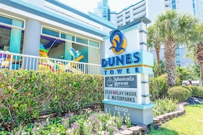 A sign for Dunes Tower with amenities including a restaurant, waterparks, and a stay & play option.