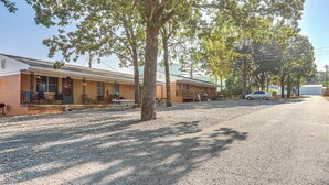 A motel with a gravel driveway, outdoor seating, and a parked car. - Shared Dock & Yard: Greers Ferry Lake Home! (Greers Ferry)