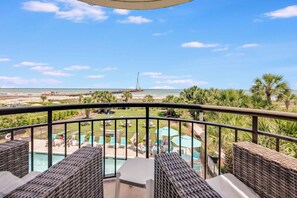 A balcony with wicker furniture, a pool, and a view of the beach and ocean. - New Beautifully Remodeled, Meridian Plaza with Pools (Myrtle Beach)