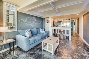 Un salon moderne avec un canapé, une table basse et un mur décoré d’une fresque représentant des poissons.